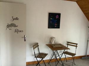 una mesa y sillas junto a una pared con un cartel. en Sylvie et Olivier, en Saint-Sozy