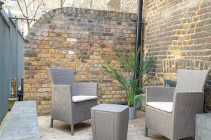 a patio with three chairs and a brick wall at Liverpool St Three Bedroom Home near Tube Station in London