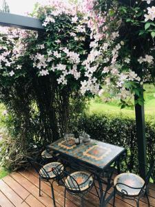 una mesa y sillas en una terraza con flores rosas en Paradise Valley River Lodge, en Rotorua