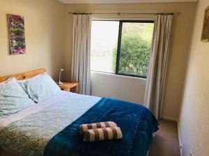 a bedroom with a bed and a large window at Paradise Valley River Lodge in Rotorua