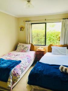 two beds in a room with a window at Paradise Valley River Lodge in Rotorua