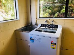 a small kitchen with a stove and a sink at Paradise Valley River Lodge in Rotorua