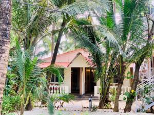 a house with palm trees in front of it at Chique Shanti Resort in Mandrem