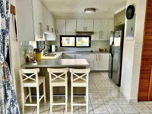 a kitchen with white cabinets and a table and stools at Entire Beach Apartment with view to El Yunque National Rain Forest in Rio Grande