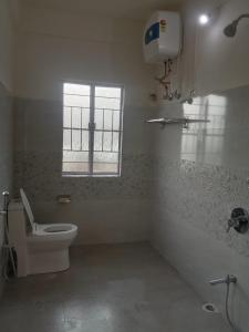 een witte badkamer met een toilet en een raam bij Picture Perfect Homestay in Cherrapunji