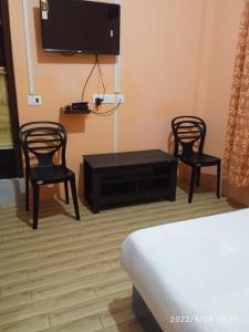 twee stoelen en een tafel in een kamer met een tv bij Picture Perfect Homestay in Cherrapunji