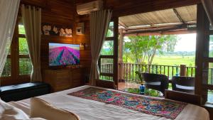 a bedroom with a bed with a television and a balcony at Nan Seasons Boutique Resort in Nan