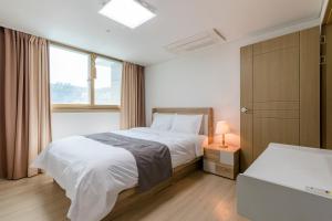 Schlafzimmer mit einem Bett und einem Fenster in der Unterkunft JS Residence Hotel Okpo in Geoje