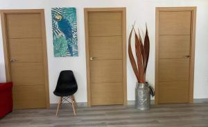 Cette chambre dispose de 3 portes en bois et d'une chaise noire. dans l'établissement Apartamento “Las Cuadras “, à Cadix
