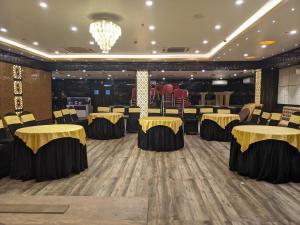 een feestzaal met zwarte en gouden tafels en stoelen bij Hotel Aavas Inn in Tezpur