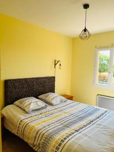 a yellow bedroom with a bed with two pillows at Jolie villa au cœur du Lauragais in Lanta