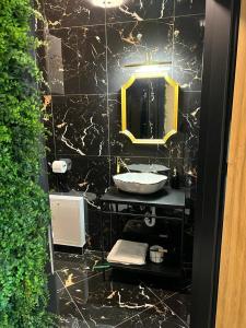La salle de bains noire est pourvue d'un lavabo et d'un miroir. dans l'établissement Jungle Apartments, à Wrocław