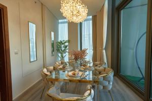 een eetkamer met een tafel en stoelen en een kroonluchter bij Magnificent 3 BR Luxury Apartment with Burj Khalifa View in Dubai