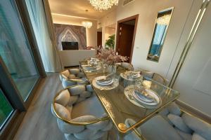 een eetkamer met een glazen tafel en stoelen bij Magnificent 3 BR Luxury Apartment with Burj Khalifa View in Dubai