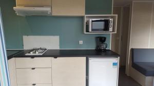a kitchen with a counter top with a microwave at Camping La Touesse in Saint-Lunaire