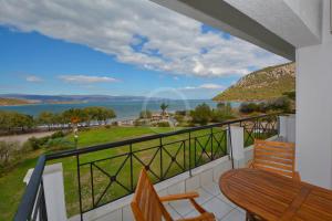 balcón con mesa, sillas y vistas al agua en Vasiliki, en Ermioni