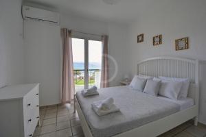 Un dormitorio blanco con una cama con toallas. en Vasiliki, en Ermioni