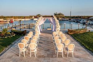- une allée de mariage avec des chaises et une tente à côté d'un port de plaisance dans l'établissement Razelm Luxury Resort, à Jurilovca