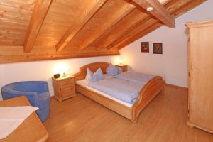 a bedroom with a bed and a blue chair at Haus Mona **** in Bad Heilbrunn