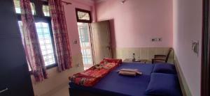 a bedroom with a blue bed in a room with windows at Athalia guesthouse in Rishīkesh