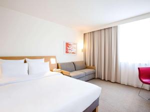 a hotel room with a bed and a chair at Novotel Wolverhampton City Centre in Wolverhampton