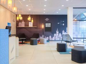 a lobby with chairs and tables in a building at Hôtel ibis Styles Auxerre Nord in Auxerre