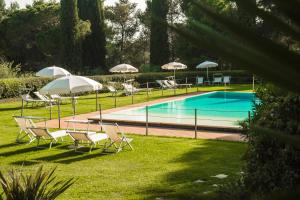 a group of chairs and tables with umbrellas next to a pool at Fattoria di Magliano Winery in Magliano in Toscana