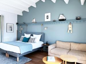 a bedroom with a bed and a couch at Les Hautes Mers - Fontenille Collection in L'Ile d'Yeu
