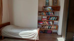 a bedroom with a bed and bookshelves filled with books at Гостевой дом Гарни in Garni