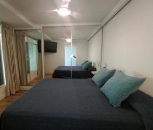 1 dormitorio con 1 cama grande con almohadas azules en Primera línea playa Puerto Santa María vistas infinitas Limpieza excepcional PARKING en El Puerto de Santa María