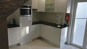 a kitchen with white cabinets and a sink at Zimbra Blue Apartment in Sesimbra