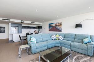 a living room with a blue couch and a table at Lorne Chalet Apartment 40 in Lorne