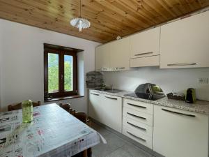 a kitchen with white cabinets and a table and a window at CASAVERDERELAX in Domodossola
