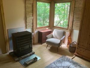 ein Wohnzimmer mit einem Herd und einem Stuhl in der Unterkunft Bungalow im Wald am See - Biberspur in Zieko
