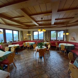 un restaurante con mesas, sillas y ventanas en Hotel Pension Berghof, en Schladming
