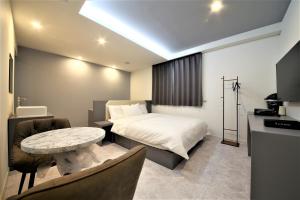 1 dormitorio con 1 cama, mesa y sillas en Namuneulno hotel, en Busan