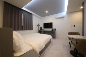 1 dormitorio con cama, mesa y TV en Namuneulno hotel, en Busan