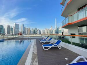 3 Liegestühle und ein Pool auf einem Gebäude in der Unterkunft Lively pop apartment on the Business Bay Canal in Dubai