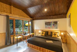 a bedroom with a bed and a table and chairs at The Hosteller Kasol, Riverside in Kasol
