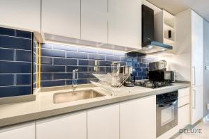 a kitchen with a sink and blue tiles on the wall at Urban Studio at MAG 318 Business Bay by Deluxe Holiday Homes in Dubai
