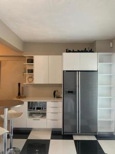een keuken met witte kasten en een roestvrijstalen koelkast bij Home Suite Hout Bay in Kaapstad
