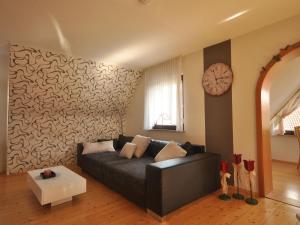 a living room with a couch and a clock on a wall at Lovely Apartment in Frankenberg with Barbecue in Frankenberg