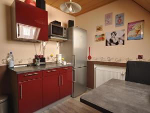 cocina con armarios rojos y nevera de acero inoxidable en Lovely Apartment in Frankenberg with Barbecue, en Frankenberg