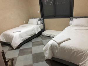 2 camas en una habitación con suelo a cuadros en villa blanche tifnit, en Tifnit