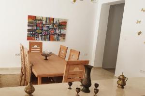 Maison plain-pied avec piscine chauffée في تونس: غرفة طعام مع طاولة و لوحة على الحائط