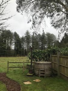 a wooden fence and a barrel with a plant in it at Sky Cabin. Cosy Forest Log Cabin 3 night minimum in Wareham