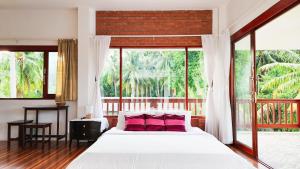 una camera da letto con un grande letto con cuscini rosa di Baan Bhuwann Holiday Apartment a Ban Chalok Lam