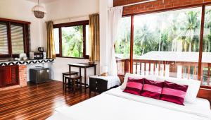 Baan Bhuwann Holiday Apartment في تشالوكلوم: غرفة نوم بسرير ابيض ومخدات حمراء