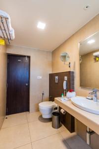 a bathroom with a toilet and a sink and a mirror at Cygnett Inn Ramachandra in Kurmannapalem