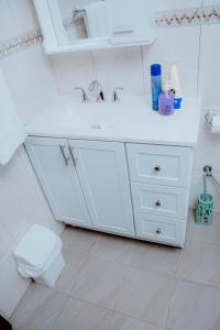 a white bathroom with a sink and a toilet at Broadbills Haven apartment in Kampala